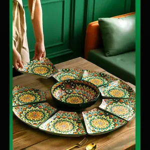 Detail view of bohemian ceramic tableware set with green mandala pattern on wooden table.