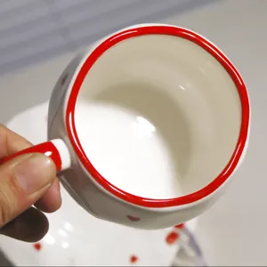 Detalle de taza de café de cerámica, taza artesanal bonita con borde rojo y corazones.