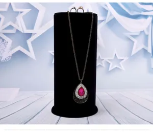 Black velvet jewelry display stand cylinder holder with elegant teardrop crystal necklace.