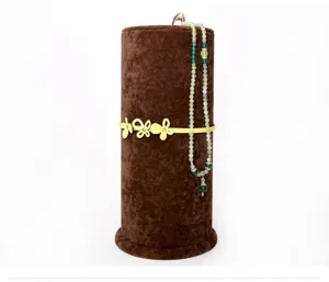 Brown velvet vertical jewelry display stand with decorative floral band and green beaded necklace.