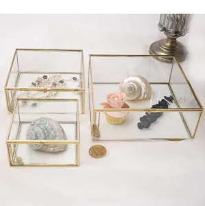 Glass jewelry box detail view, gold metal frame display tray for small decorative items.