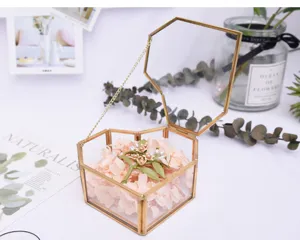 Close-up of heart-shaped brass glass jewelry box with pink preserved flowers detail shot.