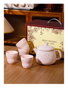 Vue détaillée d'un ensemble de théière et tasses en céramique rose dans un décor chaleureux.