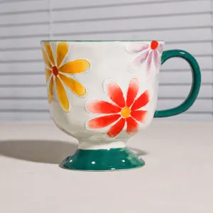 Detaillierte Ansicht der Keramiktasse mit buntem Sonnenblumenmuster und grünem Griff.