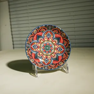 Primo piano di un piccolo piatto per salsa in ceramica con mandala, dettaglio colorato.