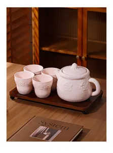 Gros plan détaillé d'un service à thé en céramique rose avec motifs floraux en relief.