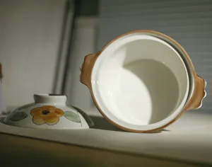 Keramische soepkom detailweergave, toont binnenkant en deksel met bloemmotief en bruine rand.