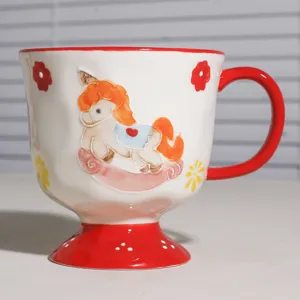 Nahaufnahme Detail der Keramiktasse mit süßem Schaukelpferd Muster und rotem Sockel Griff.