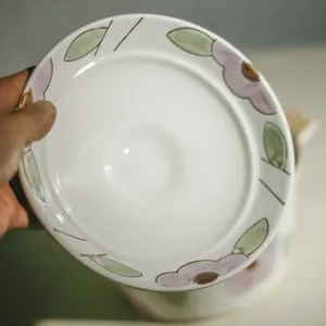 Keramische soepkom deksel met handgeschilderd bloemdessin, elegant servies detail.