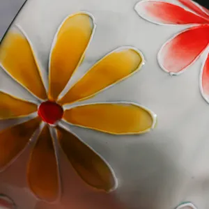 Nahaufnahme einer Keramiktasse mit exquisiter Relief-Blumenbemalung und glänzender Glasur.