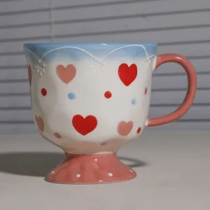 Grosse keramische Fruehstueckstasse mit Herzen, rosa Henkel und elegantem Standfuss fuer Kaffee.