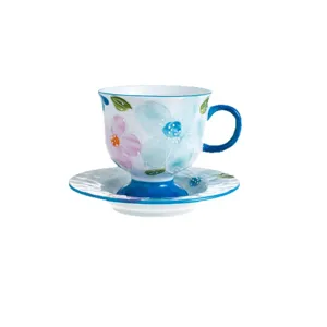 Ceramic coffee cup and saucer set featuring elegant floral design and blue handle.