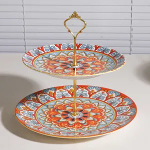 Elegante frutero de cerámica de dos niveles con diseño floral bohemio y soporte dorado.