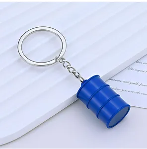 Macro view of a creative blue oil barrel charm attached to a silver metal keychain.
