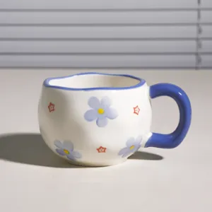 Taza de café de cerámica pintada a mano con bonito diseño de flores azules y borde irregular.
