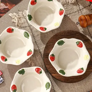 Gedetailleerde close-up van keramische fruitkom met handgeschilderd aardbeipatroon.