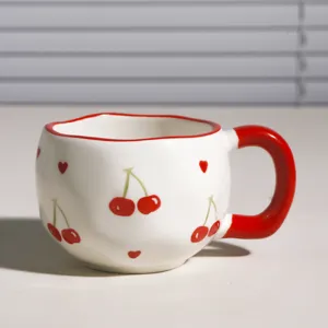 Primer plano de una bonita taza de café de cerámica con cerezas rojas pintadas a mano.