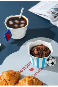 Vista di dettaglio della tazza in ceramica creativa con manico speciale sul tavolo scuro.