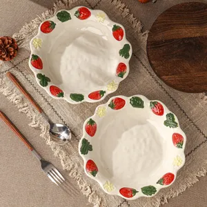 Detail van keramische aardbeienschaal met reliëf fruit en geschulpte randen op een rustieke tafel.