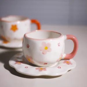 Primer plano detallado de taza de café de cerámica artesanal con bonito motivo floral rosa.