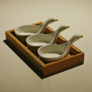 Ceramic little duck snack dish set with wooden tray, detail view of cute kitchen tableware.