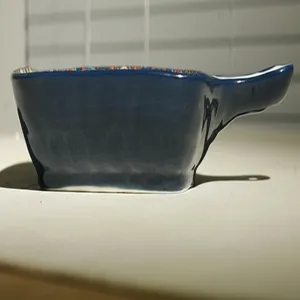 Primo piano del lato e del manico della teglia in ceramica, con smalto blu scuro.