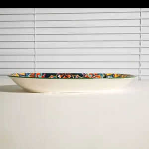 Close-up detail shot of a ceramic fish plate featuring a vibrant bohemian patterned rim.