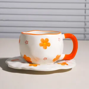Juego de taza de cafe y plato de ceramica hecho a mano con lindo diseno floral naranja.