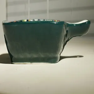 Dettaglio teglia ceramica verde, design unico manico, motivo stile bohémien interno