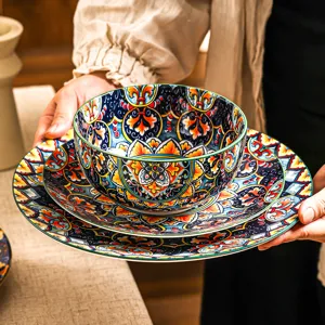 Primo piano di un set di stoviglie in ceramica boho con motivo floreale e bordo verde.