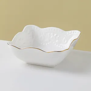 Detailed view of white ceramic bowl with gold rim and embossed floral pattern for dining.