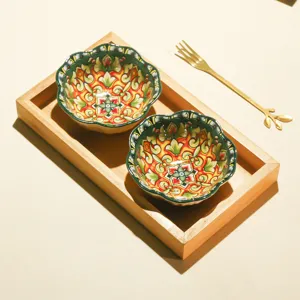 Ceramic decorative fruit bowl with floral pattern, wooden tray and golden fork detail view.
