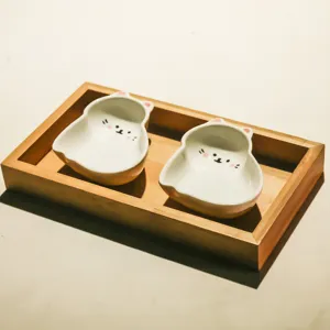 Detailed close-up of cute cat ceramic snack dishes in a wooden tray, perfect for tabletop decor.