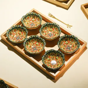 Detail view of ceramic snack bowls set in a wooden tray with floral patterns for tea table.