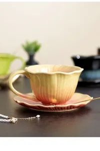 Detalle de taza de café latte de cerámica y platillo, degradado amarillo rosa en forma de flor.