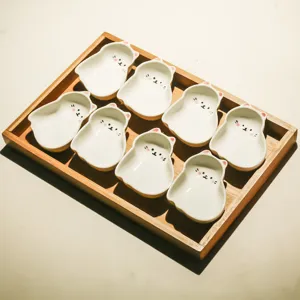 Cute cat shaped ceramic snack dish detail view with wooden tray for tea and fruit presentation.