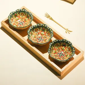 Detailed view of three ceramic floral bowls set in a wooden tray with a gold fork.