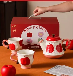 Dettaglio del set da tè in ceramica a forma di mela rossa con teiera e tazze in scatola.