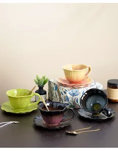 Juego de taza y platillo de café de cerámica, diseño floral con cuchara dorada.