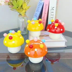 Close-up of cute ceramic mushroom storage jars with colorful ball decorations on glossy tabletop.