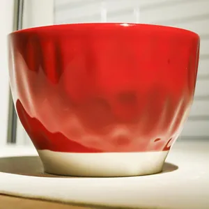 Close-up detail of the vibrant red ceramic bowl showcasing its unique hammered texture design.