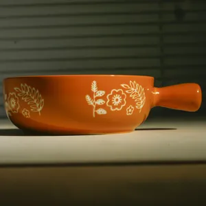 Ciotola da forno in ceramica arancione con manico stile boho stoviglie da cucina dettaglio.
