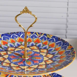 Detalle de la frutera de cerámica de 3 niveles con patrón de mandala y asa dorada.