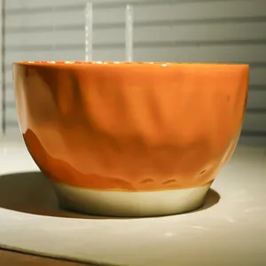 Large ceramic soup bowl with embossed orange glazed surface and textured design for kitchen use.