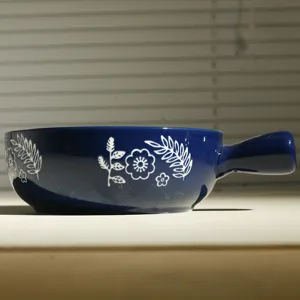 Vista dettagliata della ciotola da forno in ceramica blu scuro con motivo floreale bianco.