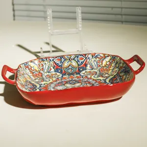 Detailed view of ceramic baking dish with bohemian floral pattern and red handles.