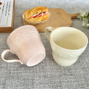 Dettaglio tazza caffè in ceramica, elegante design floreale in rilievo con manico.