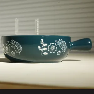 Dettaglio della ciotola da forno in ceramica con motivo floreale boho e comodo manico.