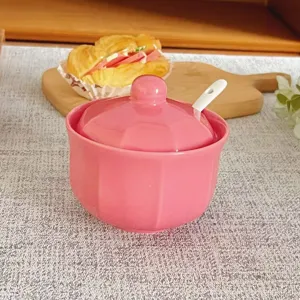 Détail pot à épices en céramique rose, récipient de cuisine avec couvercle et cuillère.