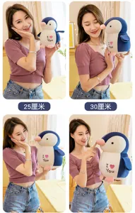 Close-up detail of cute penguin plush toy with heart embroidery, soft stuffed animal pillow.